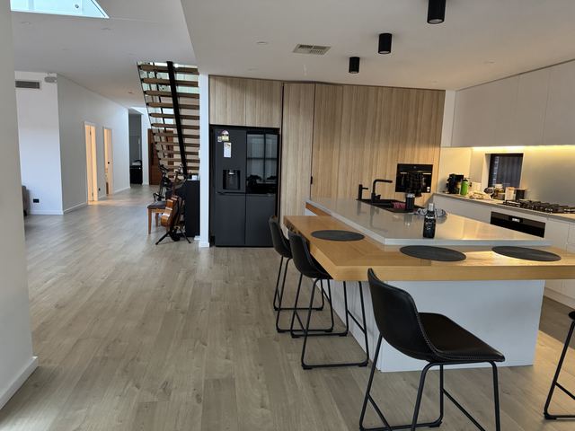 Open kitchen: a full-height oak wall around the tall units and a long island with stools.
