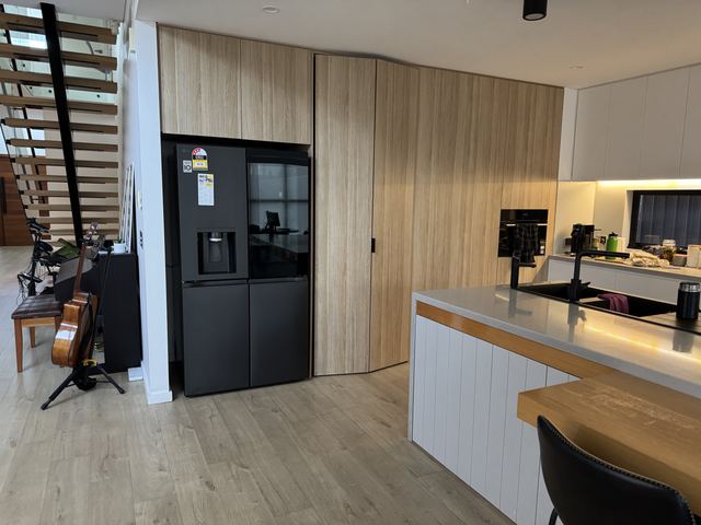 The oak wall close up, with a stone worktop and warm light under the shelves.