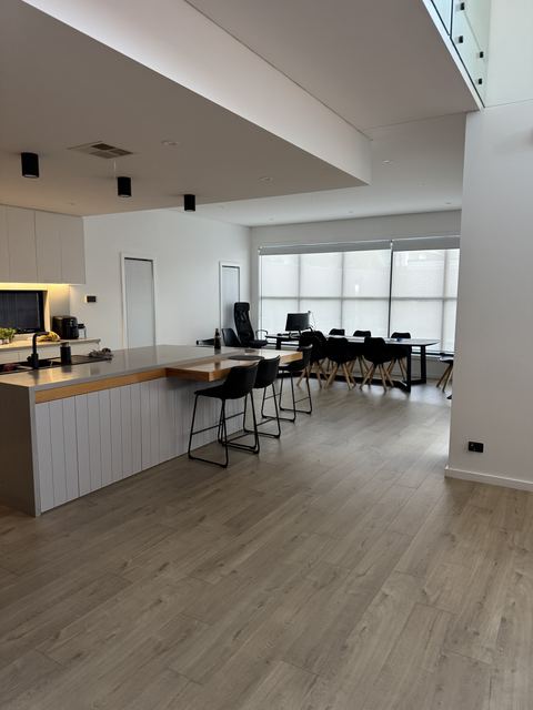 Your friends' open plan: the island under a bulkhead with short black ceiling cylinders, dining beyond.