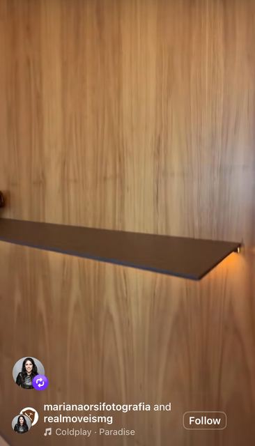 A walnut panel wall with a flush hidden door and a lit floating shelf.