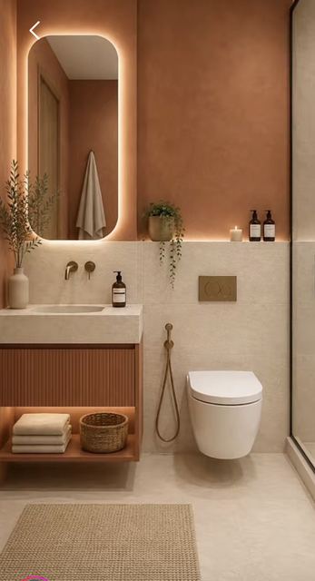 Bathroom: terracotta plaster over limestone, a backlit pill mirror, a fluted oak vanity, brass.