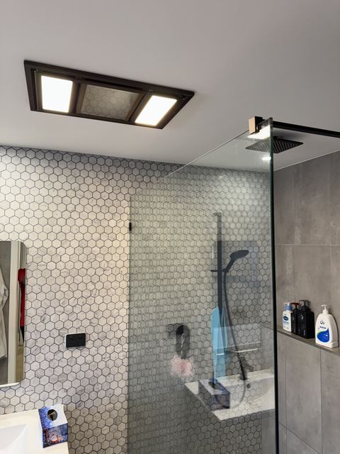Your friends' shower: white hexagon mosaic, large grey tiles, frameless glass, black fittings.