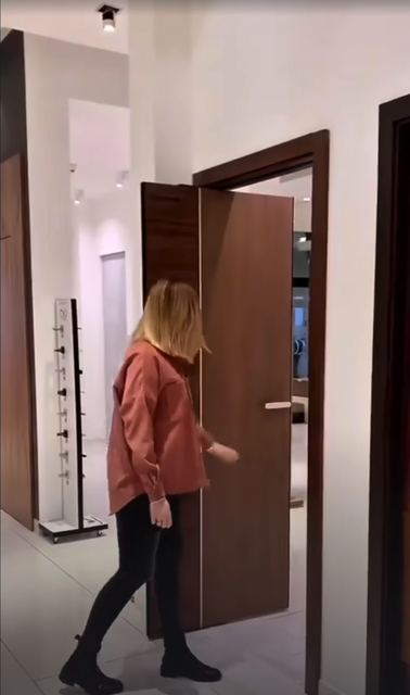 A tall walnut door in a slim frame on concealed hinges.