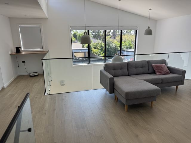 Your friends' upstairs lounge: a raked ceiling, big windows and white pendants over the stair void.