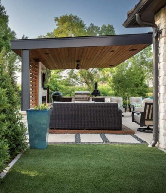 A covered terrace: a timber-lined roof on a black steel frame, an outdoor sofa and a barbecue.